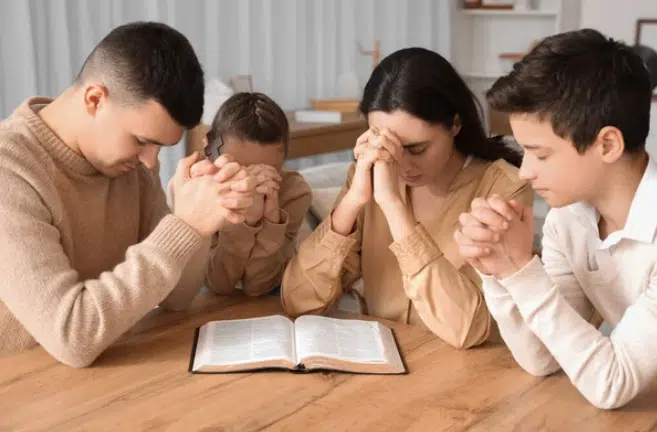 a family of four praying together | faith based relationship