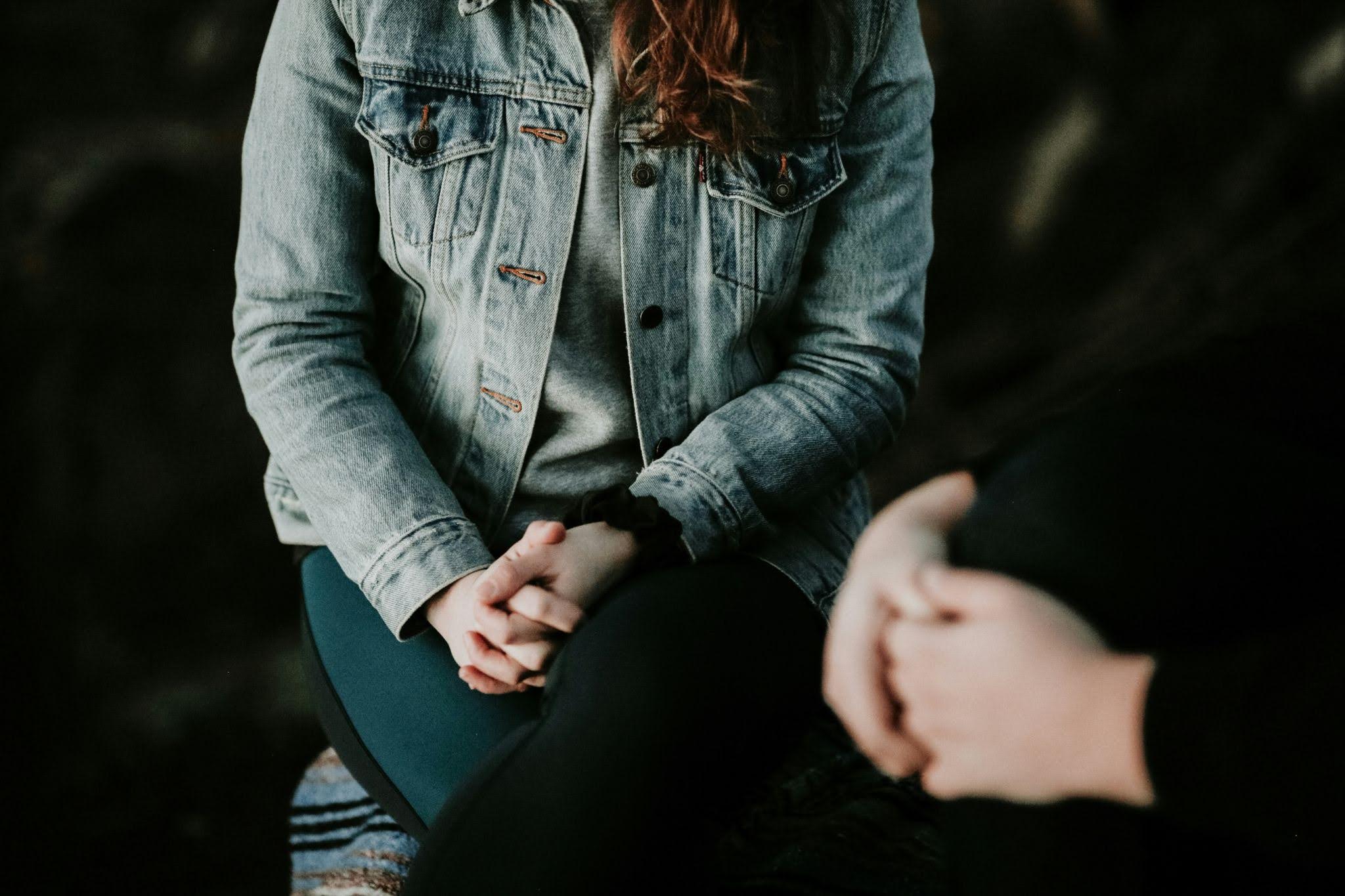 Close-up of two individuals sitting across from each other during a therapy session, showing active listening and emotional support in counseling