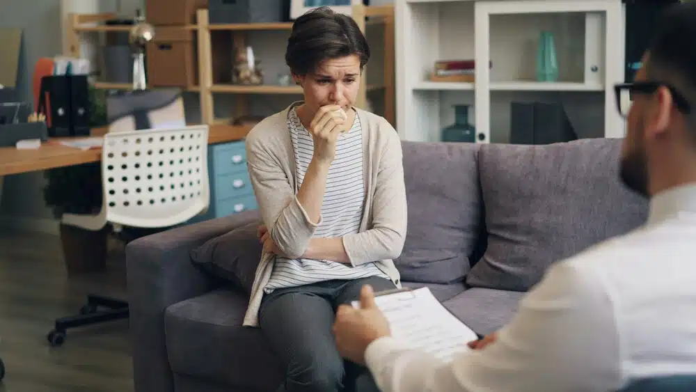 Adult looking at the counselor appearing thoughtful and emotionally burdened, representing anxiety, depression, and emotional stress counseling.