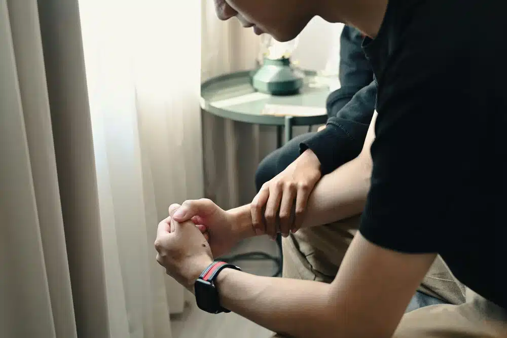 A person sitting quietly with hands clasped while receiving comfort and support during a season of grief and emotional pain.