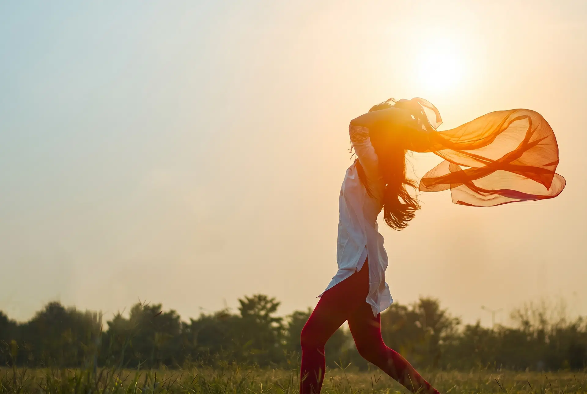 Woman standing outdoors with arms open in sunlight representing hope and freedom through Christian trauma healing