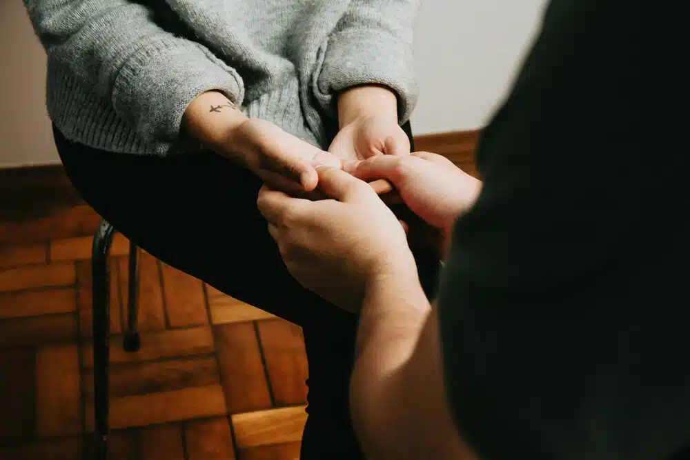 Person gently holding another person’s hands during a supportive counseling conversation about healing from narcissistic abuse.