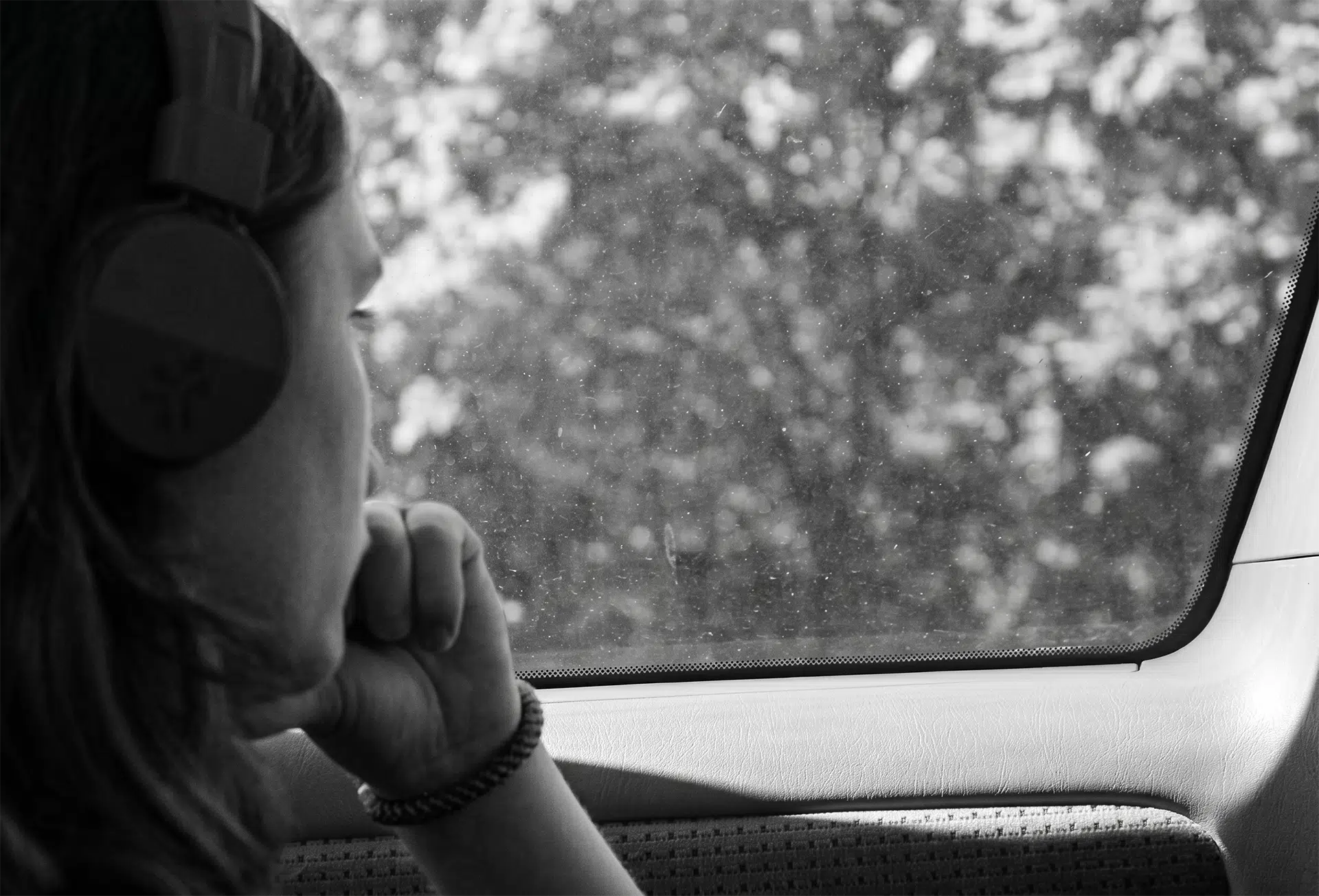 Person looking out a rain-covered car window representing isolation and emotional struggle in the context of modern digital trauma