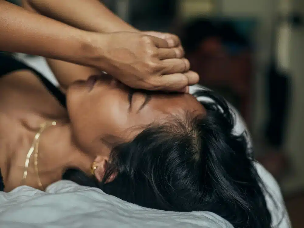 Person lying in bed covering their face while experiencing emotional exhaustion and anxiety related to narcissistic abuse recovery.