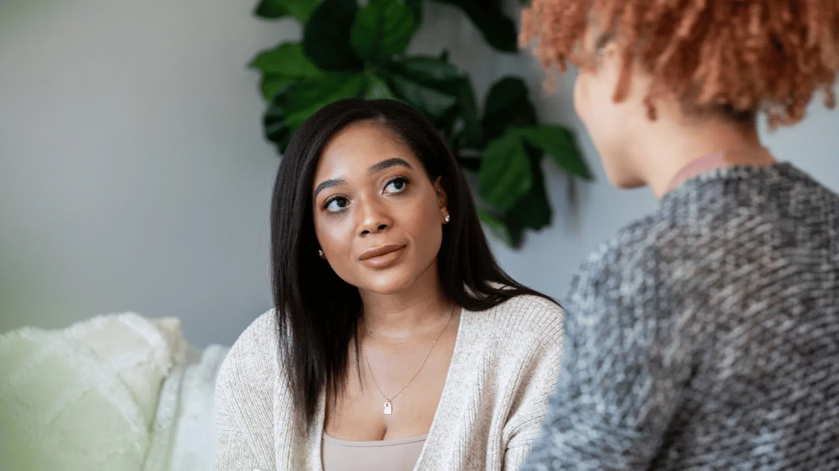 Woman listening thoughtfully during a supportive conversation in a calm living room setting, opening up about how she has been feeling.